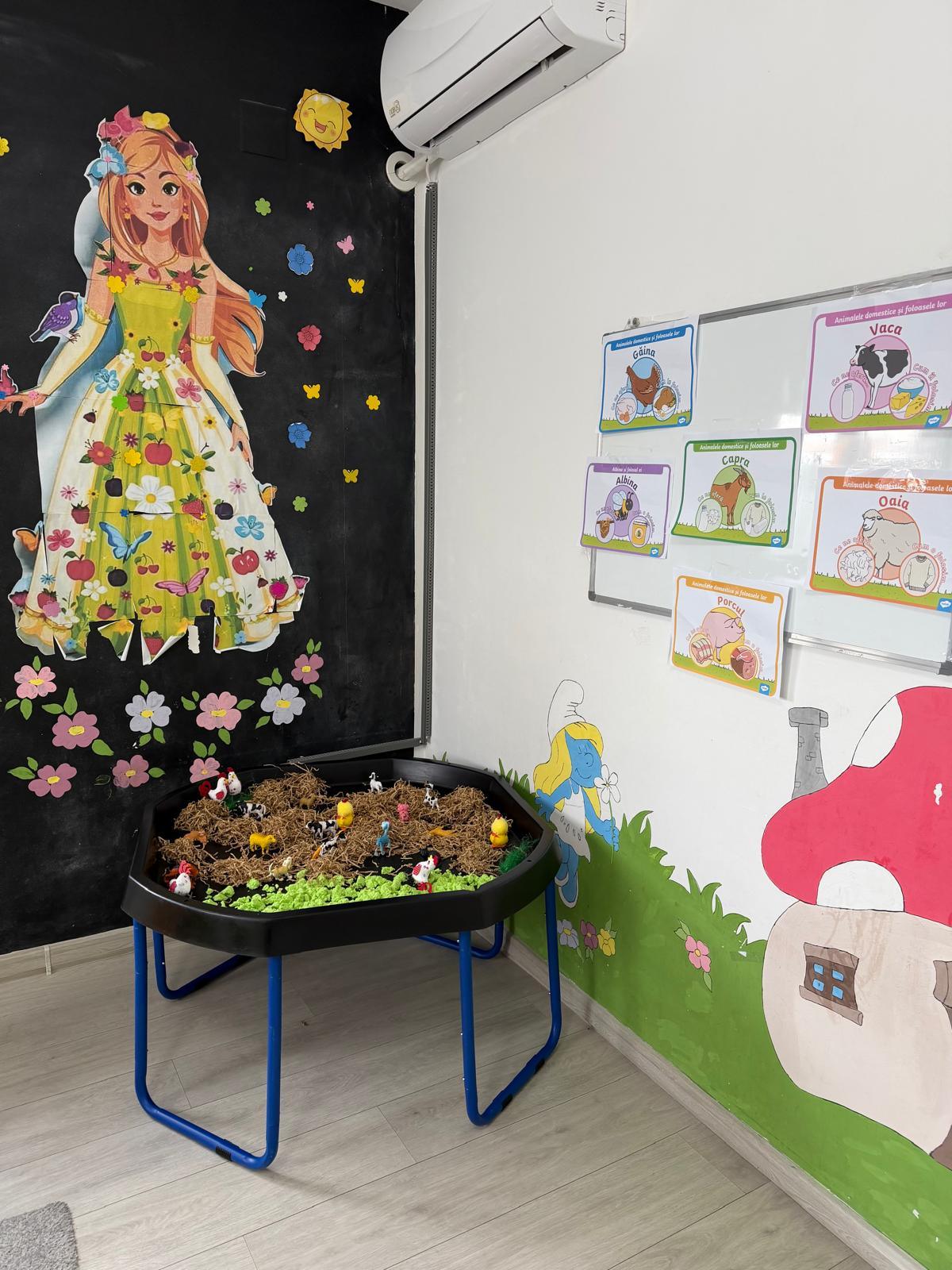 Colț de activități senzoriale cu tavă de joacă și perete pictat cu o zână