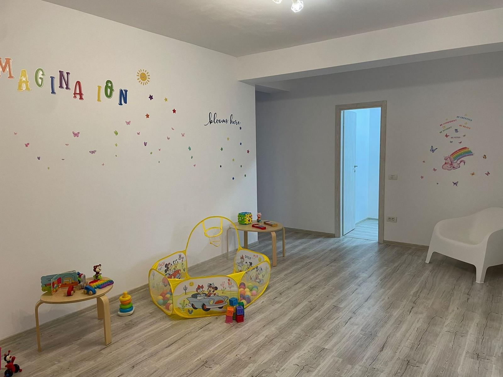 Perete pictat cu inscripția Imagination și colț de joacă cu piscină cu bile