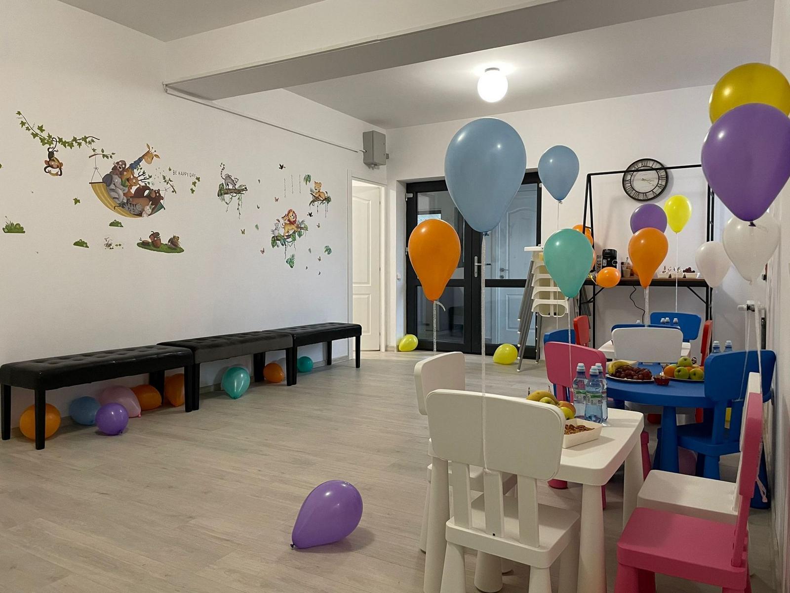 Sala mare a grădiniței, cu baloane colorate, pregătită de petrecere